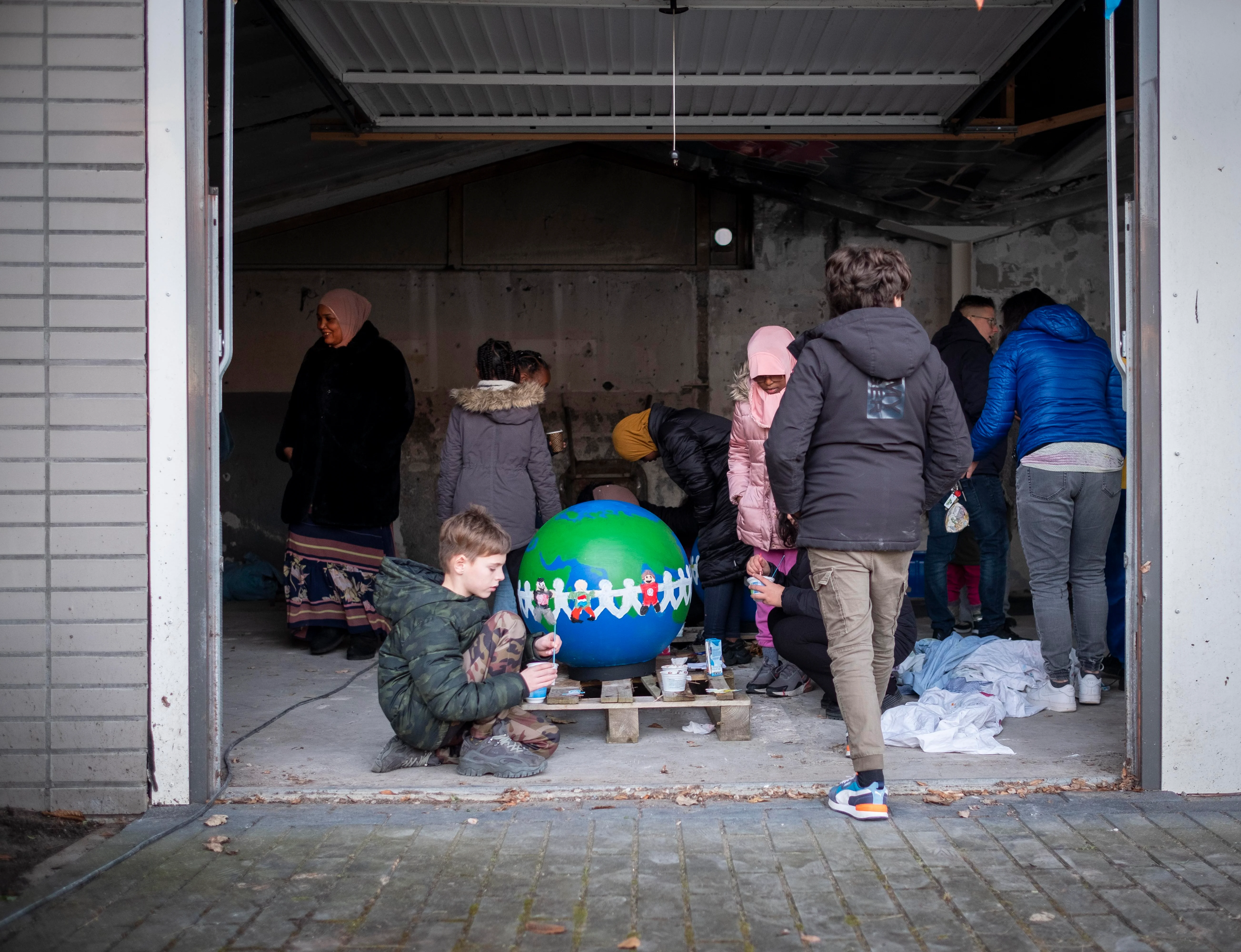 Neighborhood children paint themselves on a globe. And those bulbs are going to cheer up Overdie